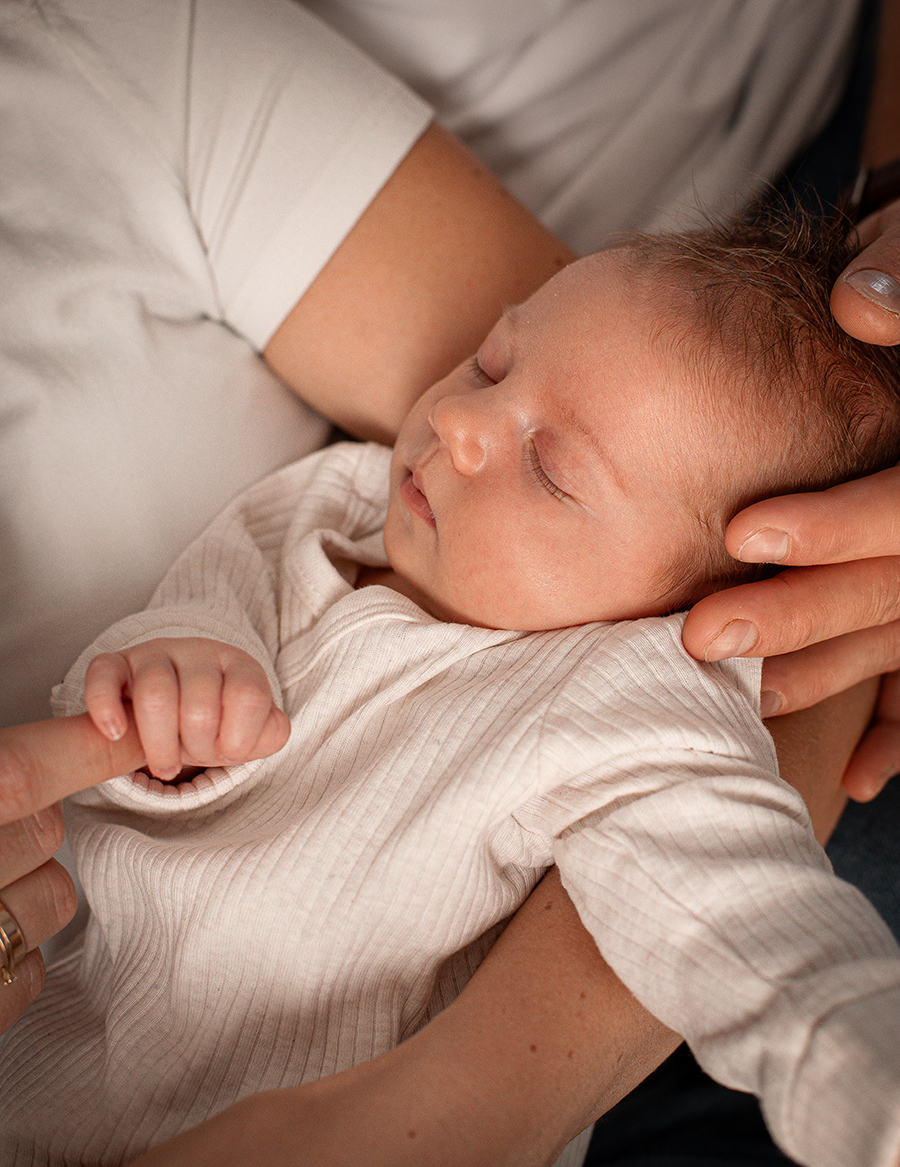 noworodek trzymający za palec podczas sesji zdjęciowej
